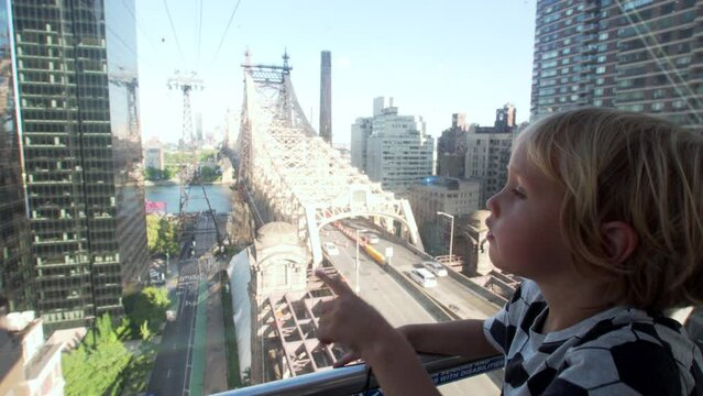 Caucasian 5 years old boy looks at the city from the Roosevelt Island Tramway, an aerial tramway in NYC that spans the East River and connects Roosevelt Island to the Upper East Side of Manhattan, USA