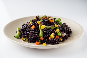 delicious black rice with vegetables on a white background
