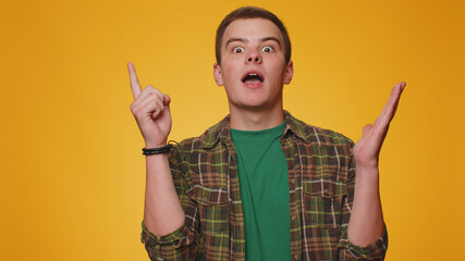 Eureka. Inspired man 20s in shirt pointing finger up with open mouth, showing Eureka gesture, solution, idea, inspiration, answer. Young adult guy boy isolated alone on yellow studio wall background
