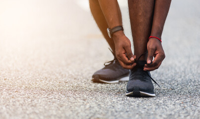 Close up Asian sport runner black man standing he trying shoelace running shoes getting ready for jogging and run at the outdoor street health park, healthy exercise workout concept - obrazy, fototapety, plakaty