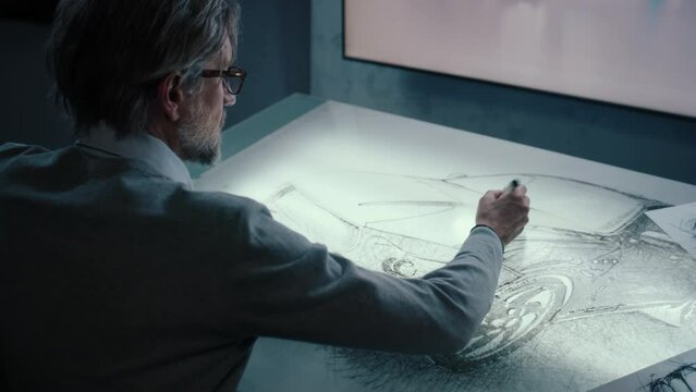 Automotive graphic designer draws sketch of the prototype model of a car with digital display graphics touch sreen, table using stylus pen in a high tech innovative laboratory.