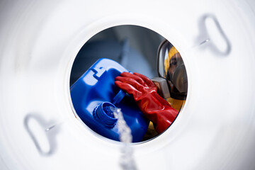 Inside barrel view of worker in protective suit mixing chemicals and making acids for industry.