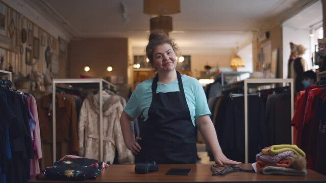 Portrait of female owner of independent clothing store wearing apron and smiling at camera. Realtime