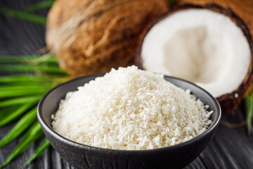 fresh natural coconut and shavings dried flakes on black wooden background