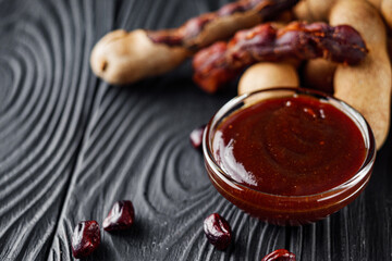 sweet and sour tamarind sauce on a black rustic wooden background - obrazy, fototapety, plakaty