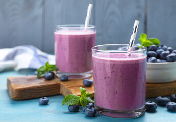 Glasses of blueberry smoothie with mint and fresh berries on turquoise wooden table, space for text