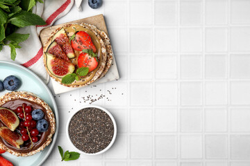 Tasty crispbreads with different toppings on light table, flat lay. Space for text