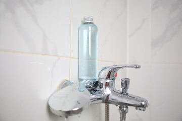 Bottle of shower gel on faucet in bathroom. Space for text