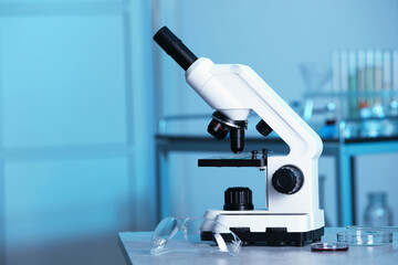 Modern medical microscope on gray table in laboratory, space for text