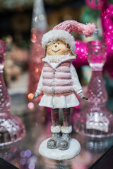 Beautiful doll in winter clothes. A small figurine toy, doll in pink clothes and accessories.