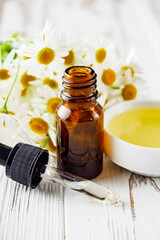 aromatic chamomile essential oil on a white wooden rustic background