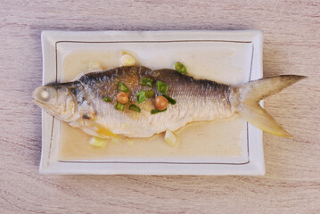 Steamed fourfinger threadfin fish with cordia dichotoma on white plate.
