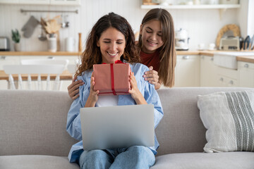 Teenage girl daughter giving birthday present to mom, child greeting congratulating mother on special occasion, smiling happy young woman receiving wrapped gift box with red bow from kid