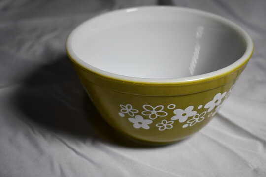 Green Pyrex bowl on white table cloth.