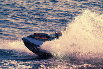 A close-up jet ski floats on the sea, splashing in different directions. The rider is not visible...