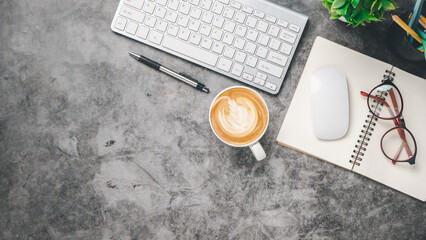 Flat lay, Dark office desk with keyboard, mouse, pen, eyeglass, notebook and coffee, Top view with copy space, Mock up.