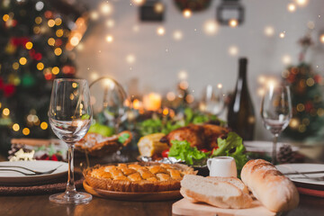 Traditional celebration. Roasted chicken, wine, vegetables salad and various food are set on table for family to celebrate together at night and Christmas tree set in the room for Christmas holiday.