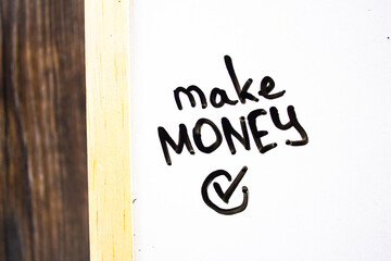 MAKE MONEY - text concept with checkmark on white board. Business, financial concept.