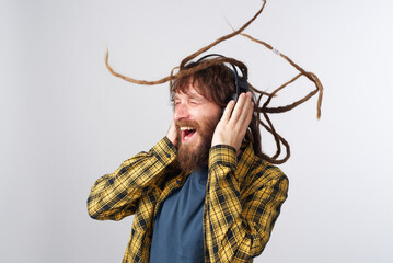 Young rastafarian reggae culture man with dreadlocks dancing to the music he's listening to on his...