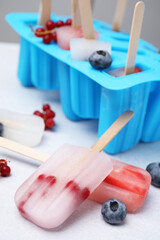 Fototapeta na wymiar Tasty berry ice pops on light table, closeup