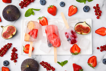 Flat lay composition with fruit and berry ice pops on light table