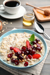 Bowl of oatmeal porridge served with berries on wooden table