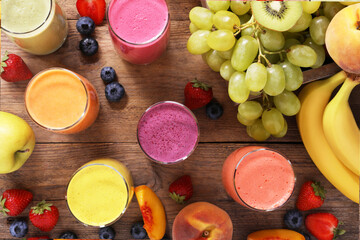 Many different tasty smoothies and ingredients on brown wooden table, flat lay
