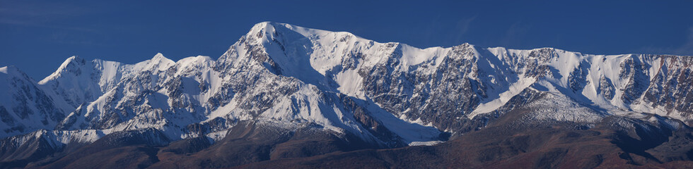 Fototapeta na wymiar Snow-capped mountain peaks, contrasting morning light, large panorama