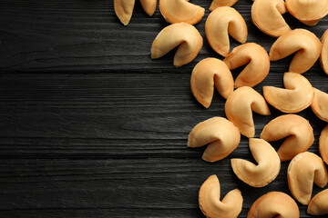 Tasty fortune cookies with predictions on black wooden table, flat lay. Space for text
