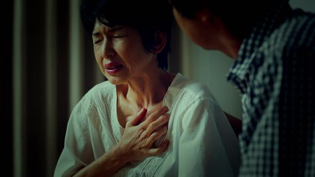 胸を押さえて苦しむ中年女性　医療イメージ