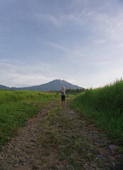 Woman walking around plantation with the dogs in the morning with mountains, blue sky, and forest as background.