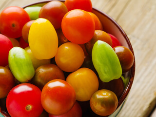 Close-up. Bright colorful tomatoes in a bowl. Beautiful culinary composition. Vitamins, antioxidants. Healthy vegetarian food. Advertising, banner.