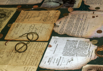 old letters, books, glasses and an inkwell with a quill on vintage wood