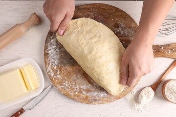 Man kneading dough at white wooden table, top view