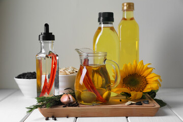 Different cooking oils and ingredients on white wooden table against light background