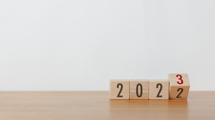 Flipping wood cube block from 2022 to 2023 text in white background. New year goal, action plan,...