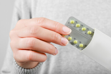 Woman holding blister with birth control pills, closeup