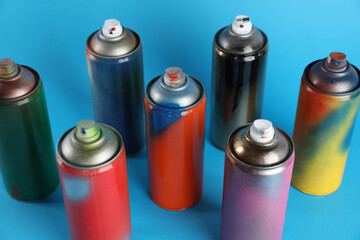 Used cans of spray paints on light blue background