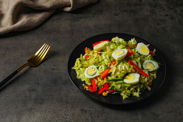 Delicious salad with Chinese cabbage and quail eggs served on black table