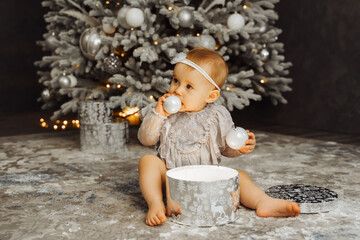 Cute little baby sits on floor. Christmas portrait, cozy style.