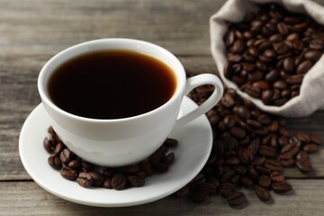 Cup of aromatic coffee and beans on wooden table