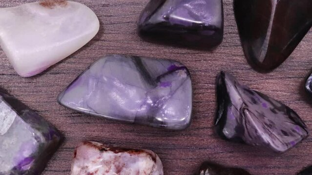 Sugilite rare jewel stones texture on black background. Moving right seamless loop backdrop.