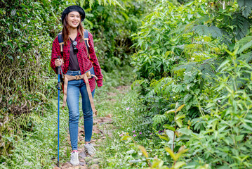 Asian woman in a hat and backpack with a trekking pole