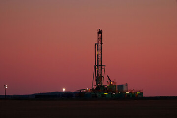 Black silhouette of oil drilling rig in the field at night.