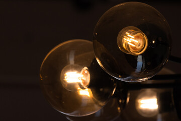 Tungsten lamps glow in round glass lampshades, close-up photo