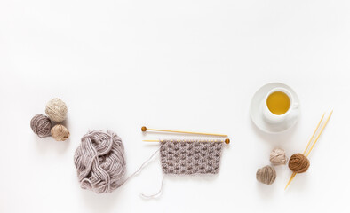 Still life with knitting supplies in pastel beige colors on white background. Balls of wool yarn,...