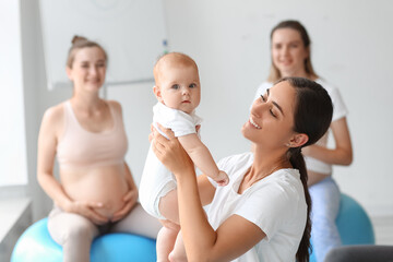 Female coach with baby and pregnant women training in gym