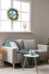 Interior of living room with sofa and window decorated for Hanukkah celebration