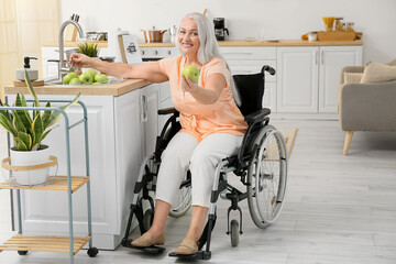 Mature woman with physical disability washing apples in kitchen