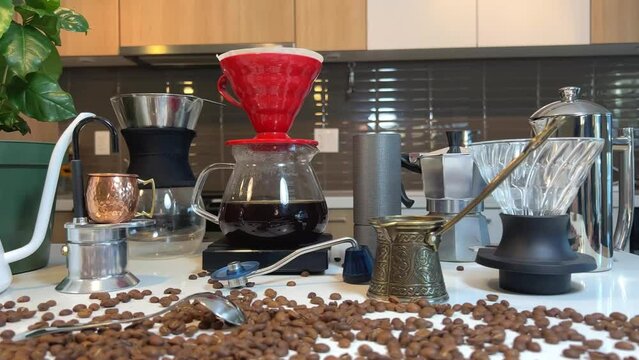 Various devices for craft coffee beans lie on the table On the white countertop in the kitchen the camera slowly floats, removing all the details in pouring coffee dripping after brewing